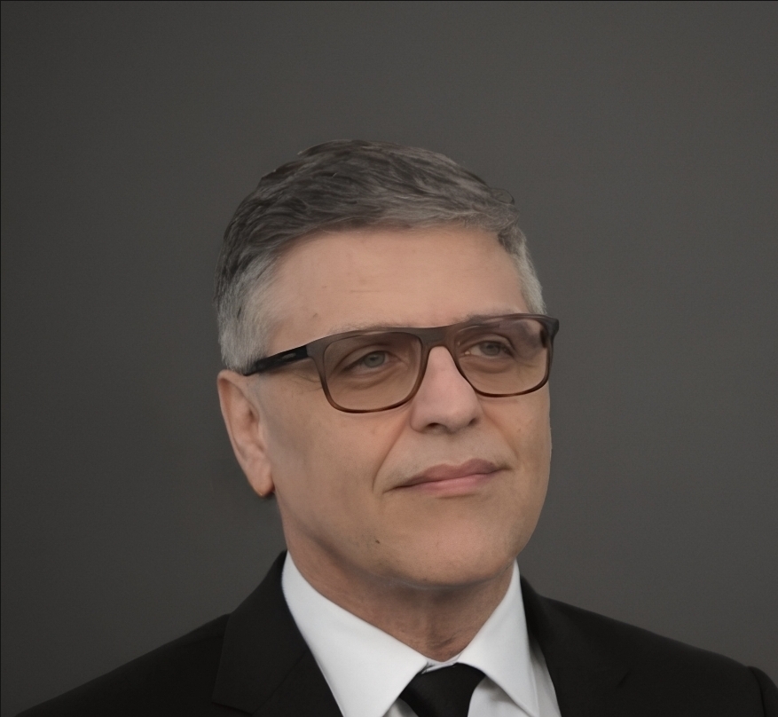 A middle-aged man wearing glasses and a suit with a neutral expression.