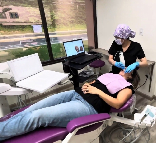 A patient undergoing a dental procedure with a dentist using a tablet.