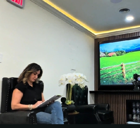 A woman reads a book in a modern living room with a TV on.