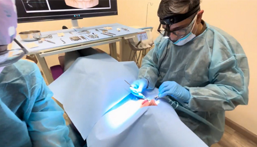 A dentist wearing protective gear treating a patient's teeth.